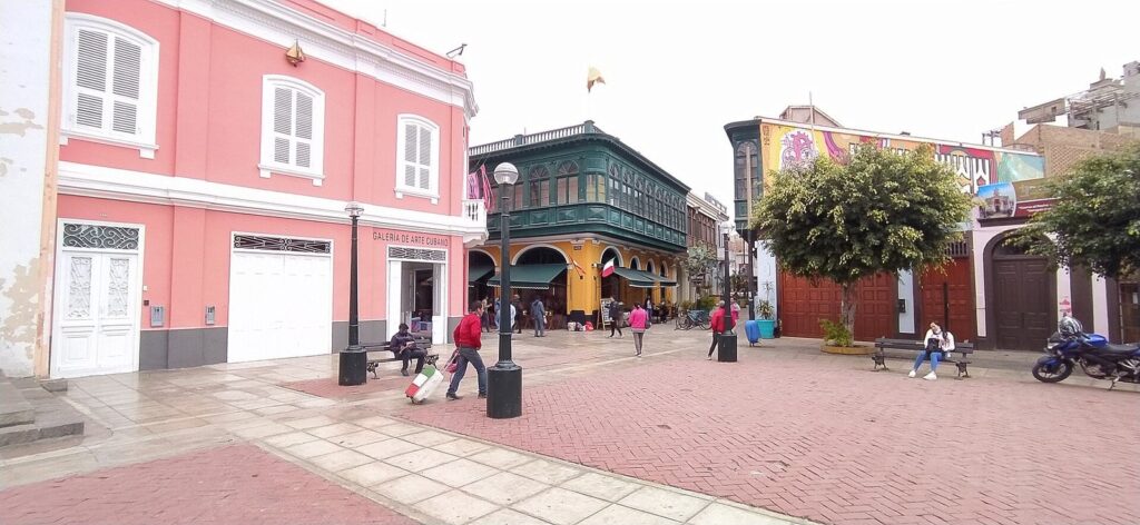Restored pink and yellow buildings with wooden balconies around a pedestrian square in Callao Monumental, Callao, Peru