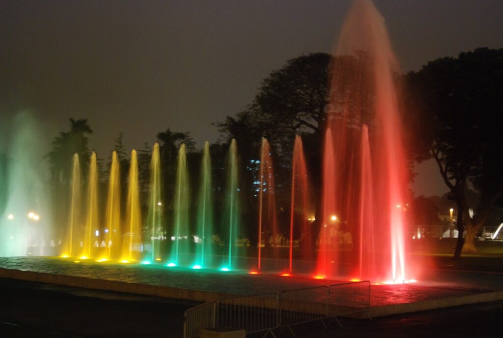 Jets of water lit red, green and yellow at night in the Magic Water Circuit in Parque de la Reserva, Lima, Peru
