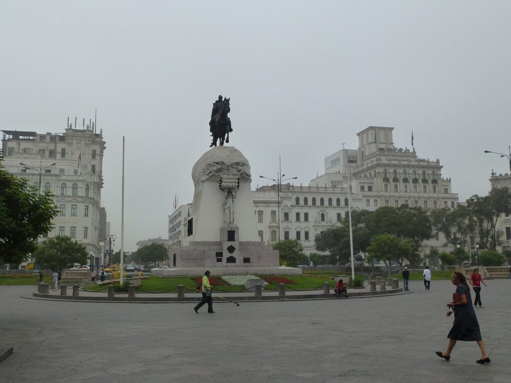 Gray garúa sky over the Plaza San Martín in Lima's historic center, with the equestrian statue and white colonnaded buildings