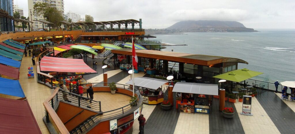 Terraces of the Larcomar shopping center on the Miraflores clifftop in Lima with shops, colorful awnings and the Pacific behind