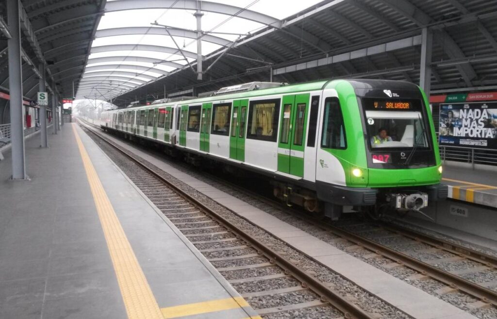 Green and white Metro Line 1 train arriving at an elevated station platform in Lima