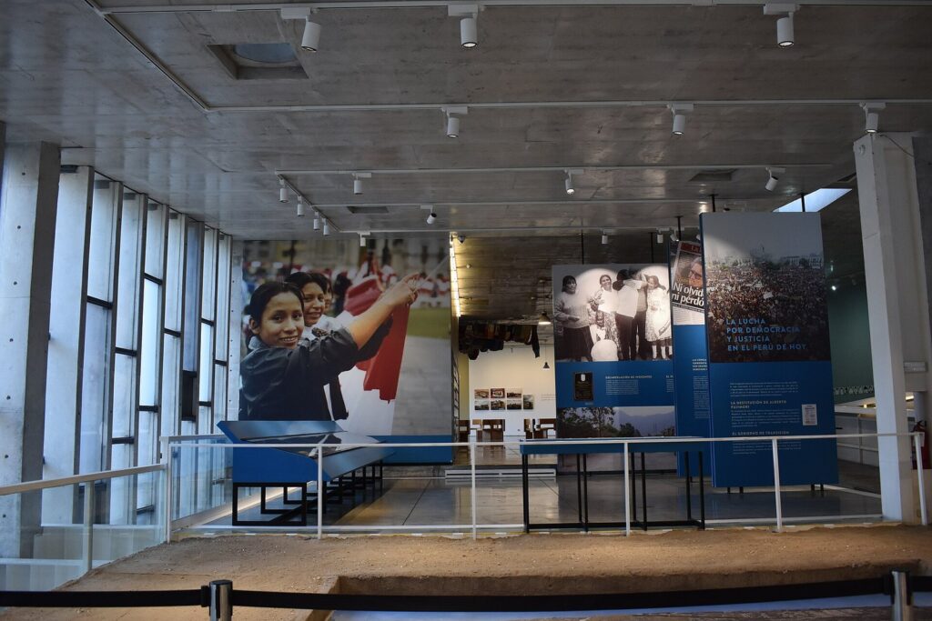 Exhibition hall of the Lugar de la Memoria in Miraflores, Lima, with photograph panels, display cases and bare concrete walls