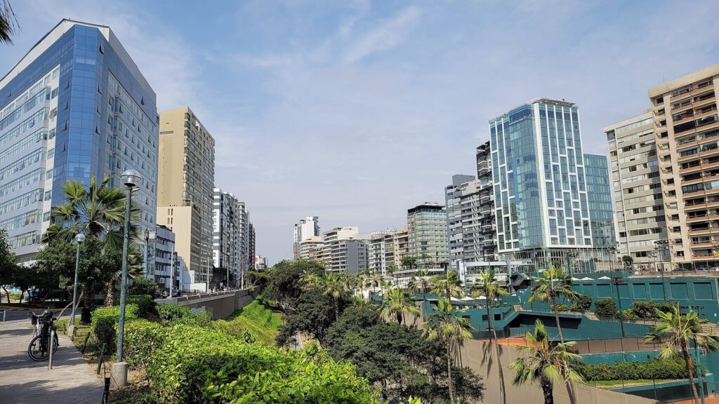 High-rise towers above palm-lined clifftop parks and tennis courts on the Miraflores malecón in Lima on a sunny day