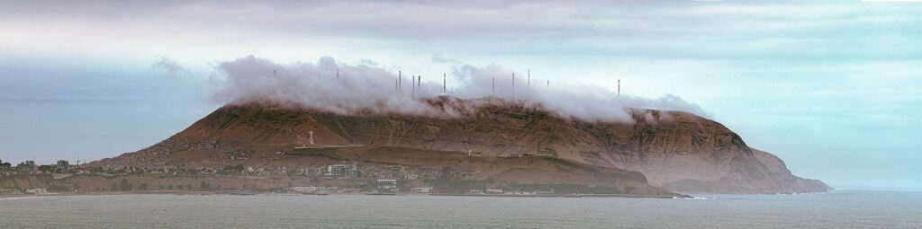 The Morro Solar headland in Chorrillos, Lima, rising from the sea with a band of low cloud over its summit