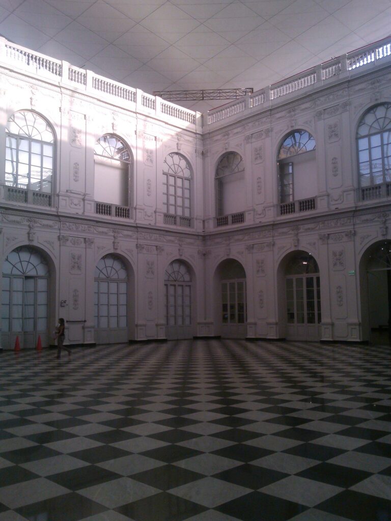 Interior hall of the Museo de Arte de Lima with arched windows on two levels around a checkerboard marble floor