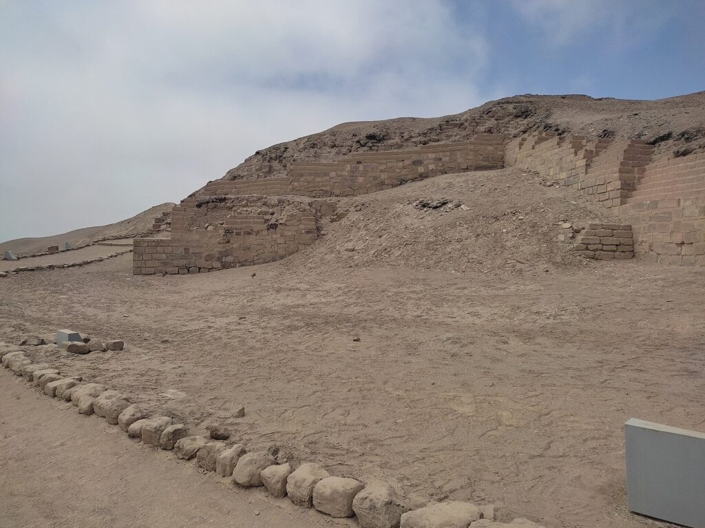 Stepped adobe terraces of the Temple of the Sun at the Pachacamac archaeological sanctuary south of Lima under a gray sky