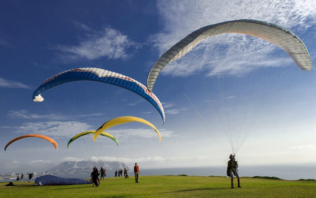 Paragliders inflating their wings on the clifftop launch field in Miraflores, one of the most popular things to do in Lima, Peru, with the Morro Solar headland behind