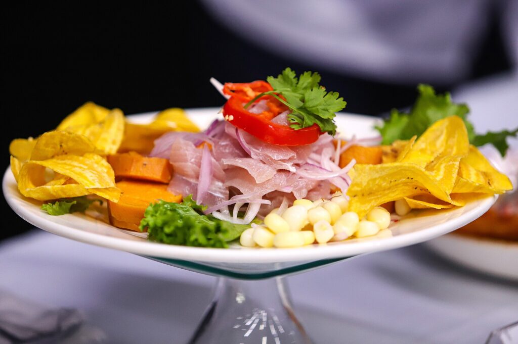 Plate of Peruvian ceviche with raw fish cured in lime, red onion, sweet potato, large-kernel corn and plantain chips