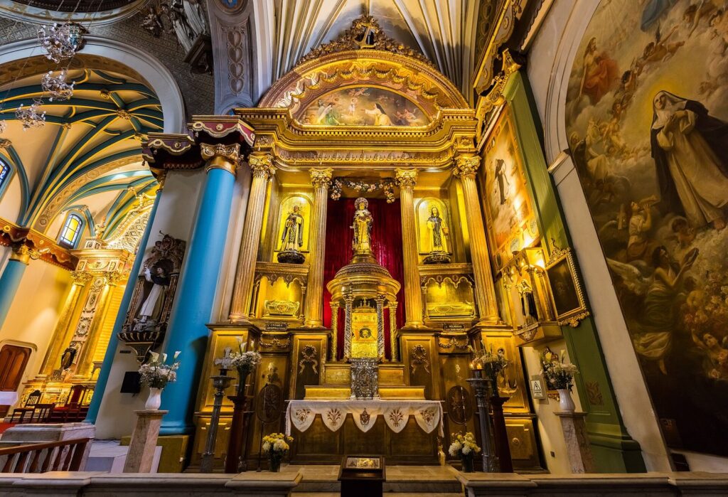 Gilded baroque altar with statues of saints under a painted vault inside the church of Santo Domingo in Lima