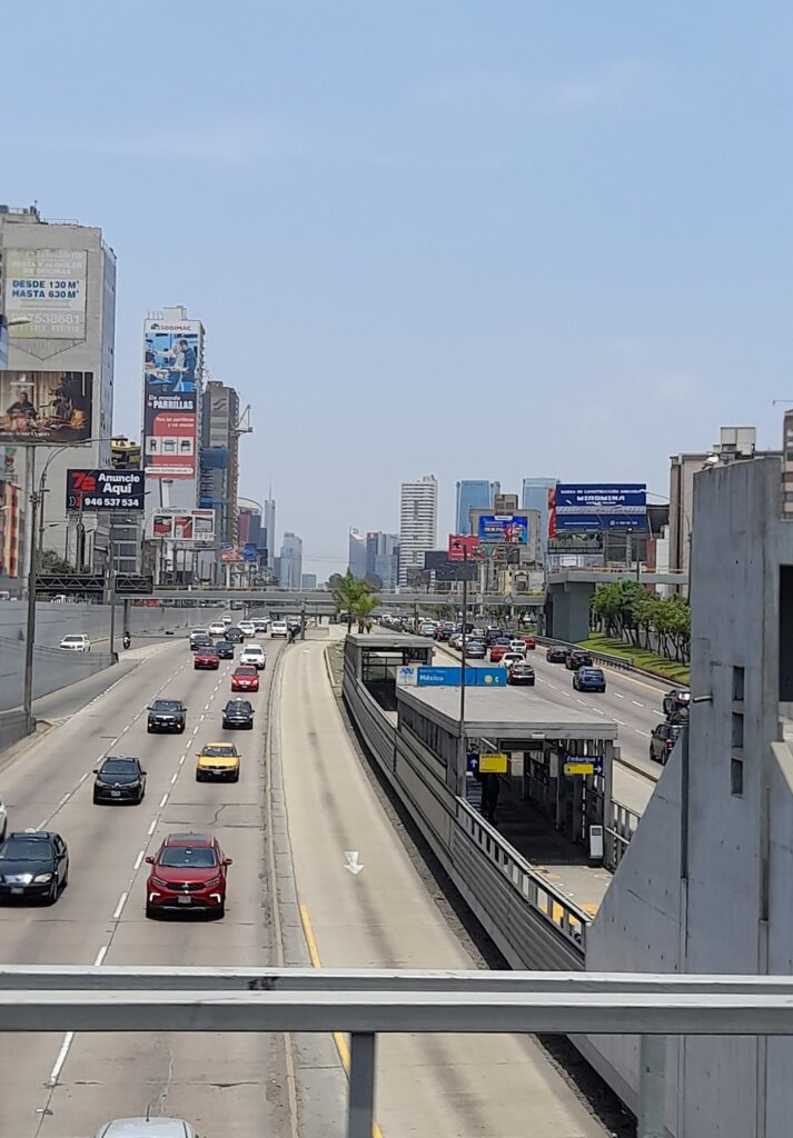 The Vía Expresa in Lima with car lanes on both sides and a Metropolitano bus station in the central corridor, under a hazy sky